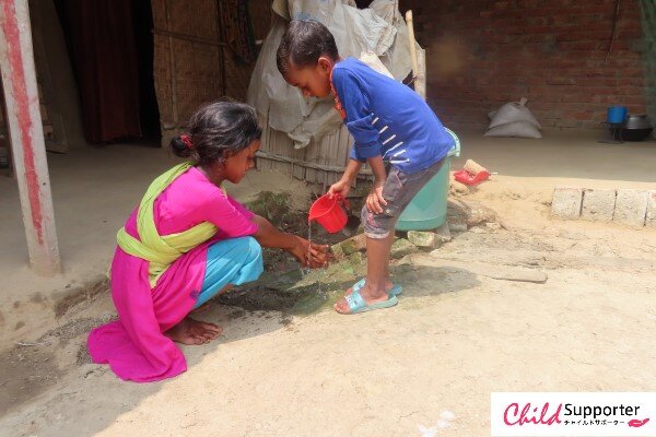 Lebio helping his sister to wash hands.jpg